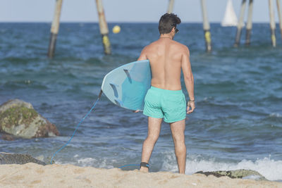 Rear view of shirtless man standing on beach