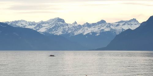 Scenic view of sea and snowcapped mountains against sky