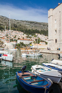 Sailboats moored on harbor by buildings in city