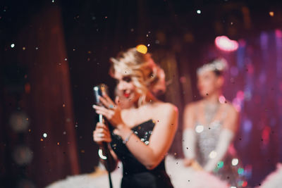 Young woman with arms raised standing at music concert