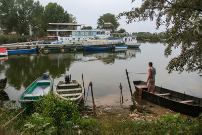 Man on boat moored in lake against sky