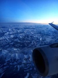 Close-up of airplane wing over sea against clear blue sky