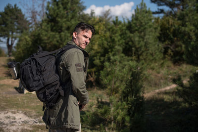Side view of young man wearing sunglasses against trees