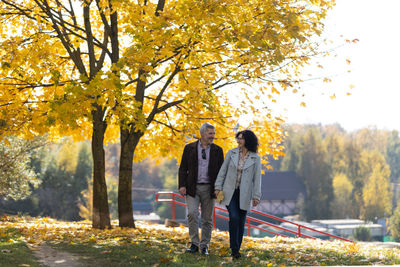 Portrait of a mature couple 50 years old walking hand by hand in an autumn park.