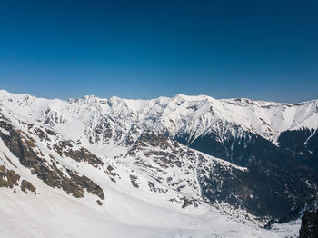 Scenic view of snowcapped mountains against clear blue sky