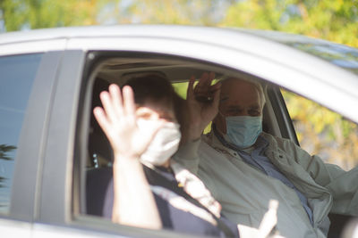 Senior couple wearing anti virus masks are driving in a car during the covid-19 pandemic