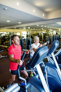 Senior man and mature woman on step machine in fitness gym