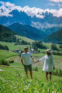 Rear view of women on field against mountains