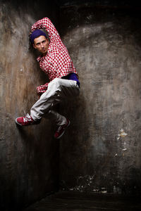 Full length of young man dancing against wall