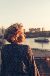 Rear view of woman standing against sky during sunset