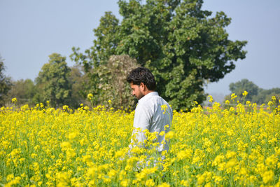 Young indian farmer at black mustard field