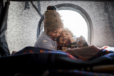 Smiling siblings sitting in roof tent