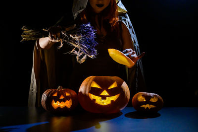 Midsection of woman with pumpkin on table