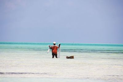 Rear view of men walking on beach against clear sky