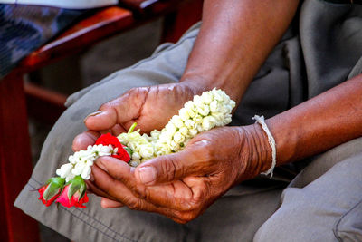 Midsection of woman holding flowers in hand