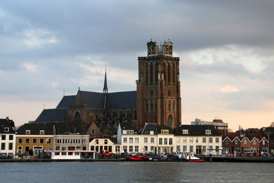 Buildings by river against sky