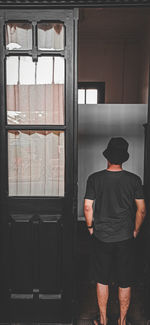 Rear view of man standing by window