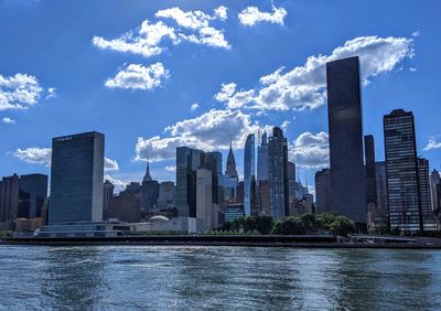 Sea by modern buildings against sky in city