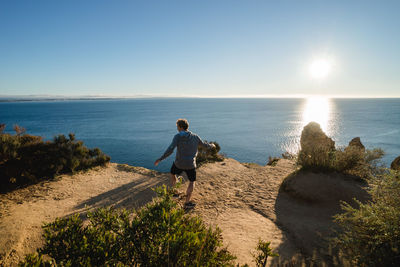 Rear view of man standing at beach against sky