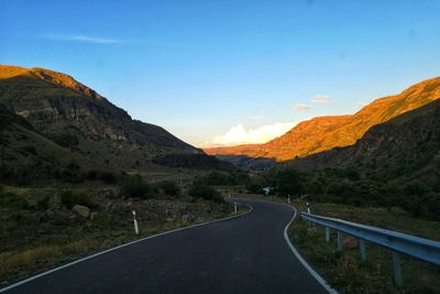 Road leading towards mountains against sky