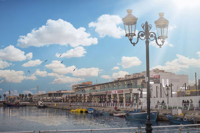 Boats moored at harbor against sky in city