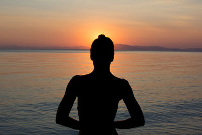 Silhouette woman looking at sea against sky during sunset