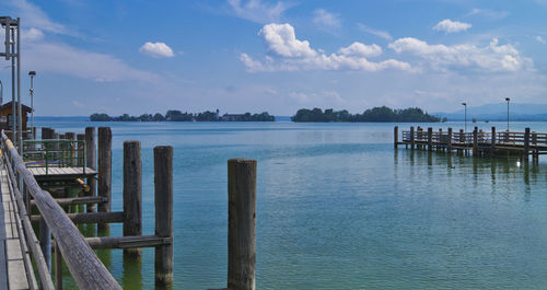 Wooden posts in sea against sky