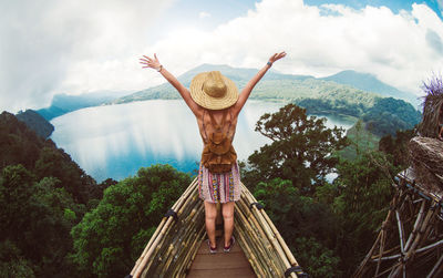 Rear view of woman standing on mountain against sky