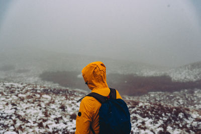 Rear view of person standing on snow covered land