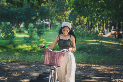 Portrait  asian woman walking with a bicycle crossing a wooden bridge in a public park