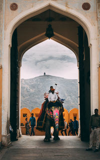 People at historic building seen through archway