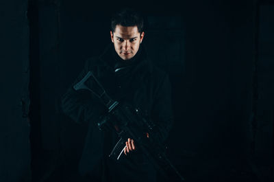 Man holding camera while standing in dark room