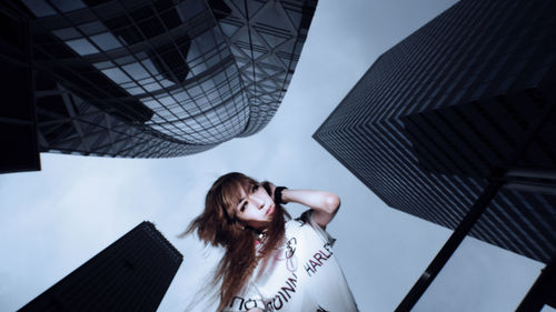 Low angle portrait of woman standing against sky