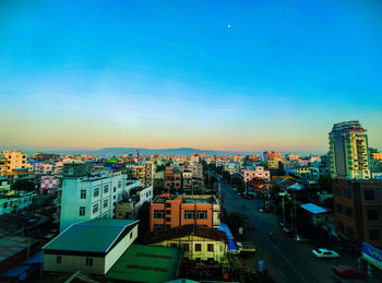 High angle view of buildings in city against blue sky