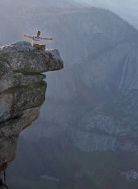 Man sitting on rock against mountain