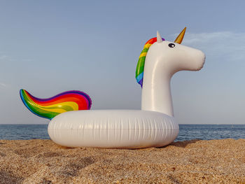 Multi colored toy on beach against sky