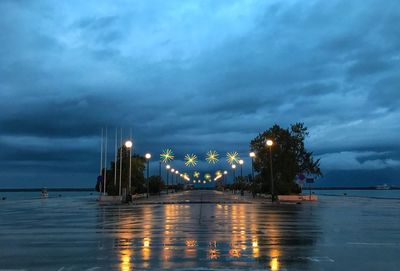 Illuminated bridge over sea against sky at night