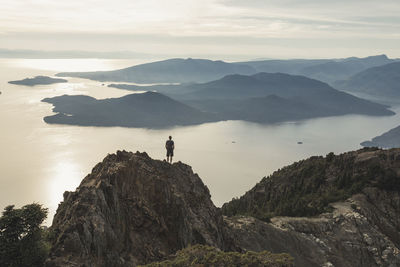 High angle view of carefree hiker standing on mountain against sky during sunset