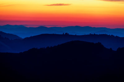 Scenic view of silhouette mountains against orange sky