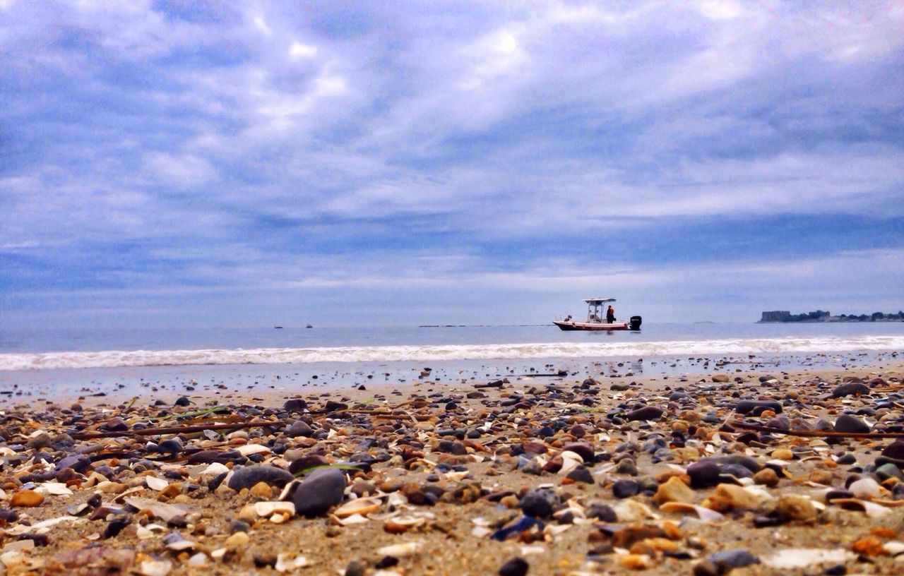 sea, water, beach, sky, horizon over water, shore, transportation, cloud - sky, nautical vessel, rock - object, scenics, tranquility, tranquil scene, beauty in nature, nature, stone - object, mode of transport, boat, pebble, cloudy