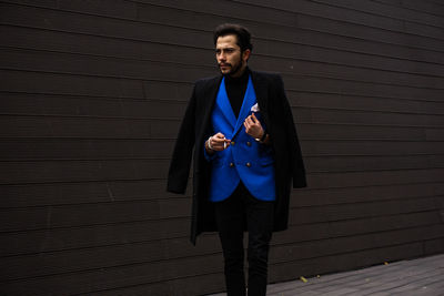 Young man in suit standing against wall