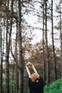Rear view of woman stretching in forest