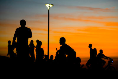 Silhouette people against sea during sunset