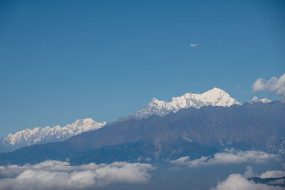 Low angle view of snowcapped mountains against blue sky