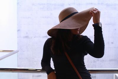 Woman wearing hat while leaning on railing