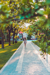 Rear view of woman walking on footpath in park