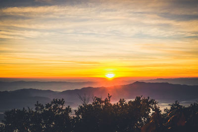 Scenic view of silhouette mountains against orange sky