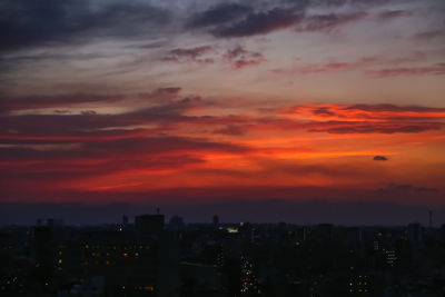 Silhouette buildings against cloudy sky during sunset