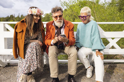 People sitting on bench and using phone