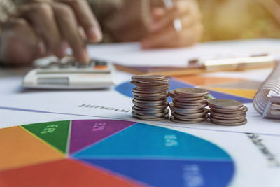 Close-up of coins stack with man working on desk 